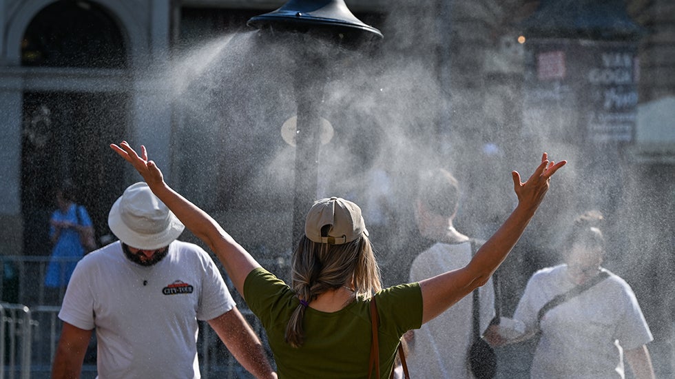 A woman opens her arms to catch the fine spray from a water misting station