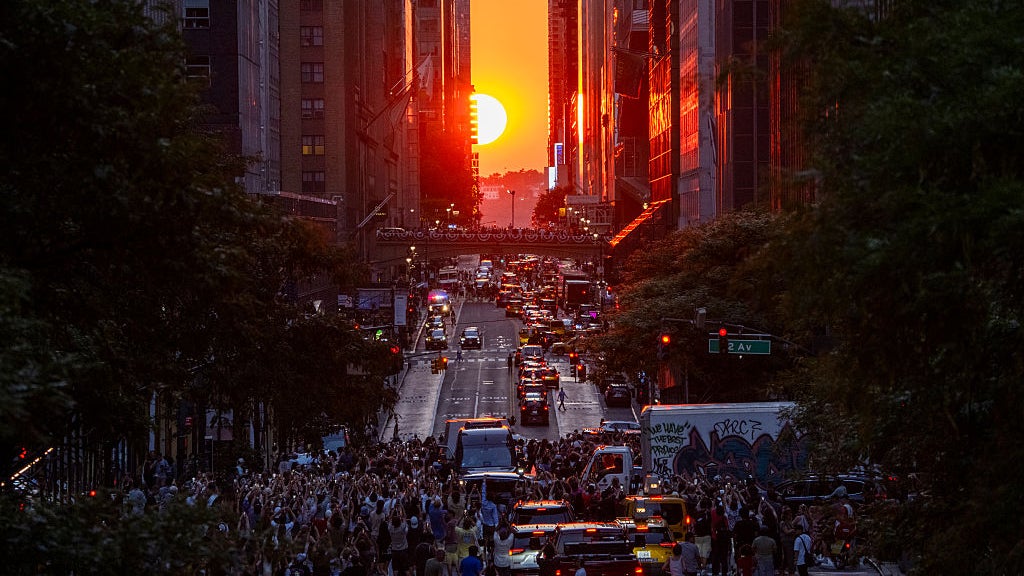 Hundreds of cars and people fill 42nd Street near New York's Times Square to see the sunset align perfectly between the city's skyscrapers.