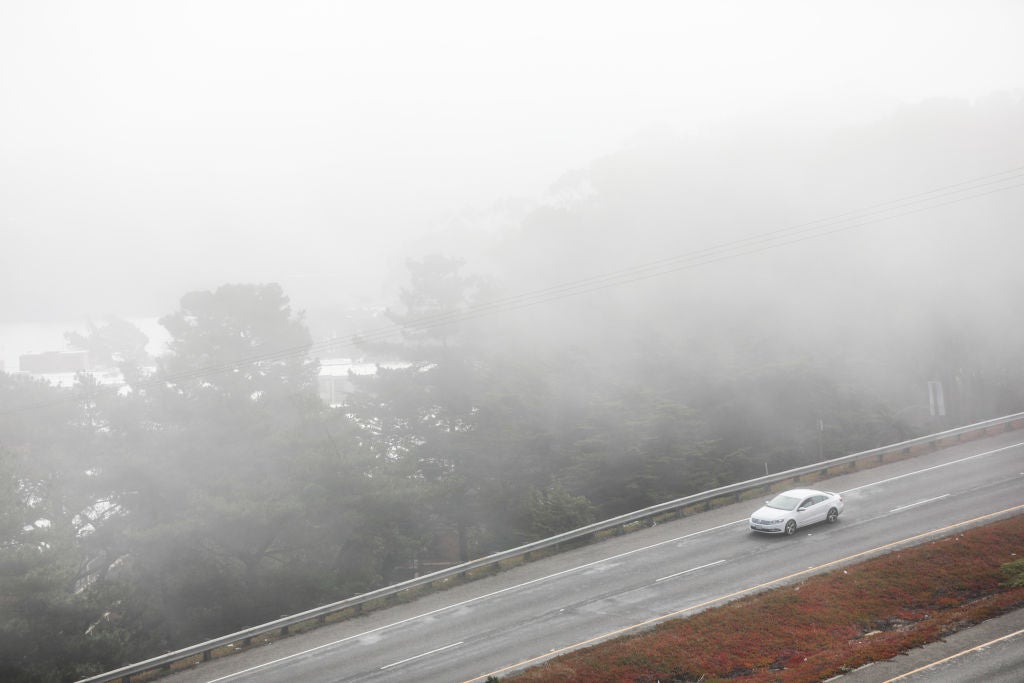 Car driving through road covered in fog. 