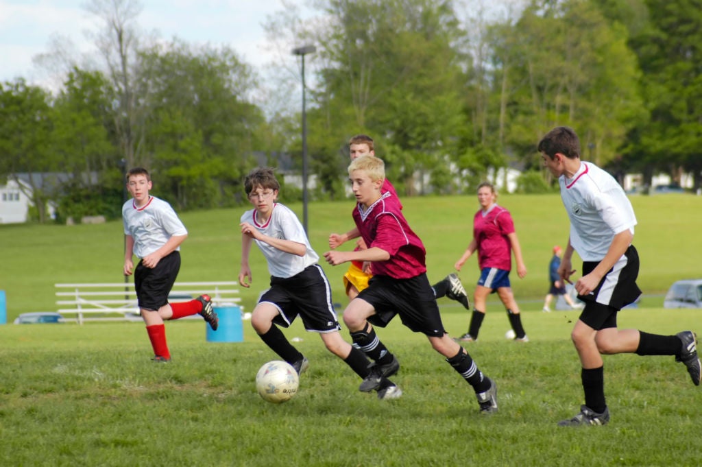 Youth soccer players kicking the ball down the field. 