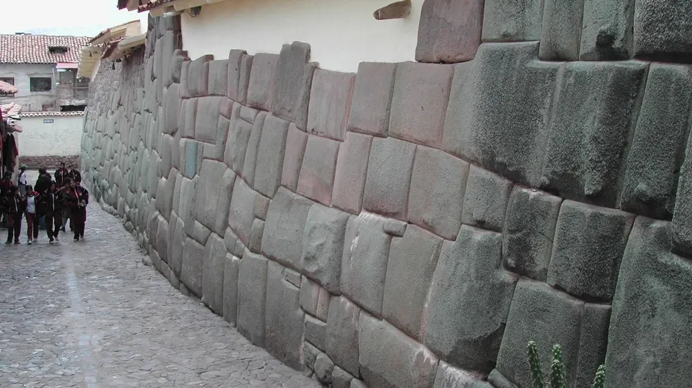 Ancient Inca stone wall with precisely fitted polygonal stones along a cobblestone street in Cusco, Peru