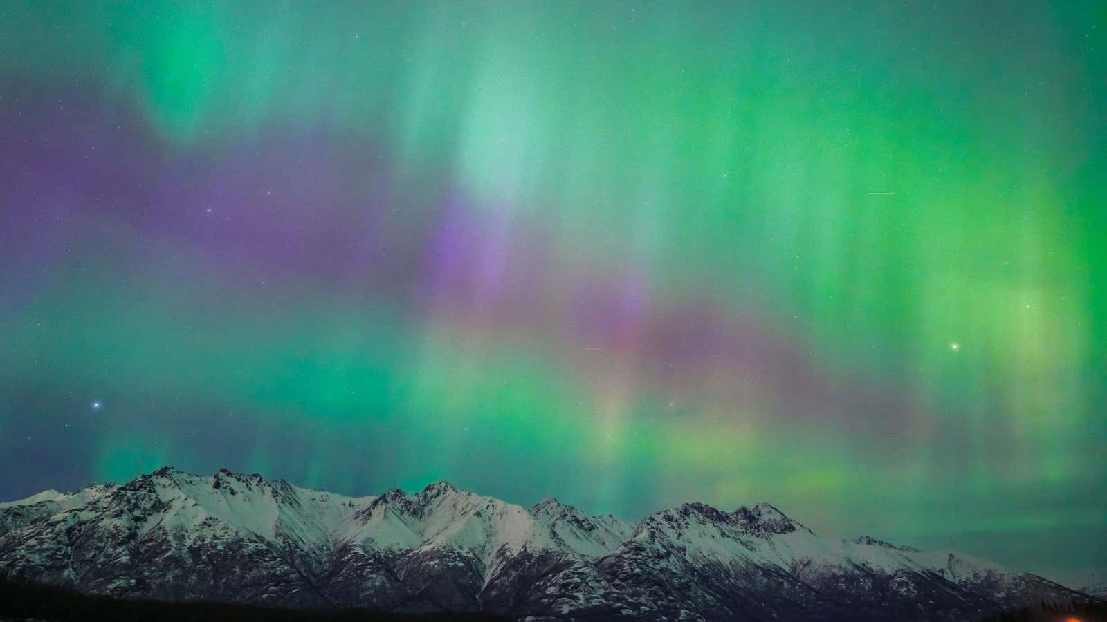 Northern Lights (Aurora Borealis) illuminate the night sky with vivid purple and green hues above a distant cityscape following a strong solar storm coinciding with the spring equinox in Fairbanks, Alaska, on March 20, 2026. The display peaked after combined coronal mass ejections from the sun on March 16 and 18 intensified geomagnetic activity. The National Oceanic and Atmospheric Administration (NOAA) reported G2 and G3 level geomagnetic storm conditions throughout the night. The aurora band expanded southward, becoming visible across Alaska and in 18 states across the U.S.