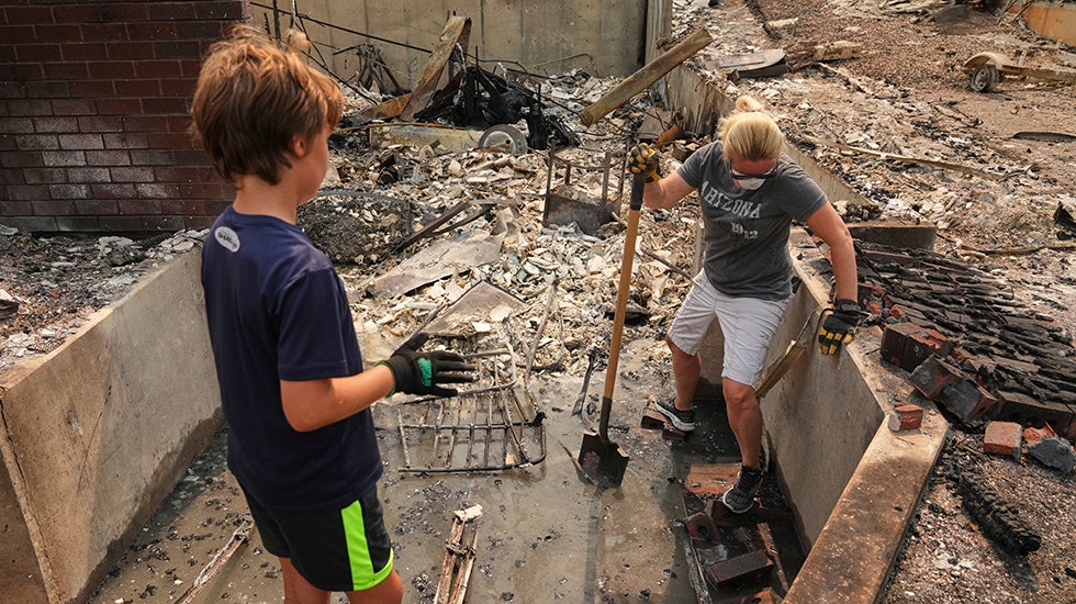 A mother and son sift through debris of a burned home