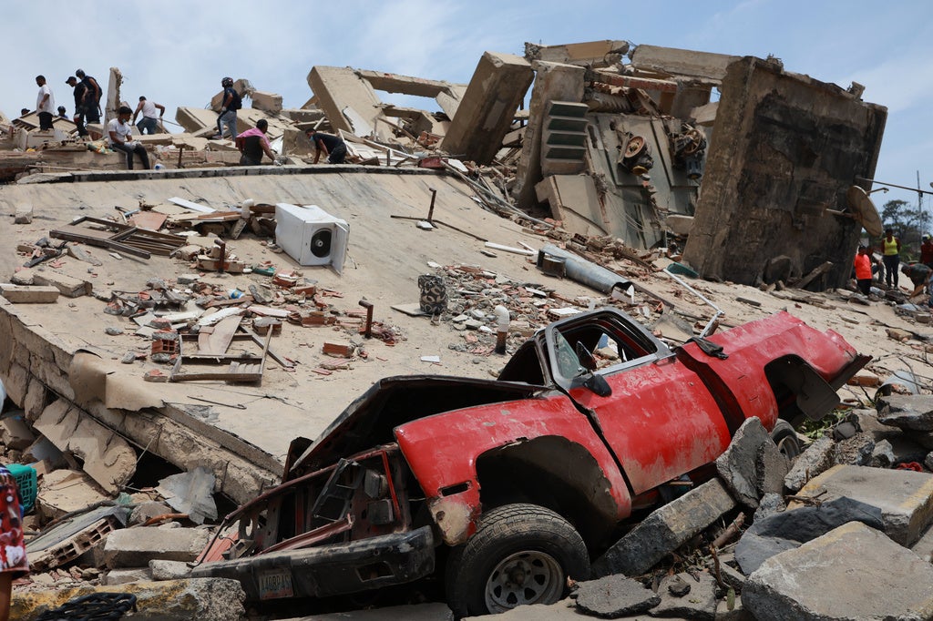 Earthquake aftermath scene with collapsed concrete buildings, crushed red car, and rescue workers searching through debris