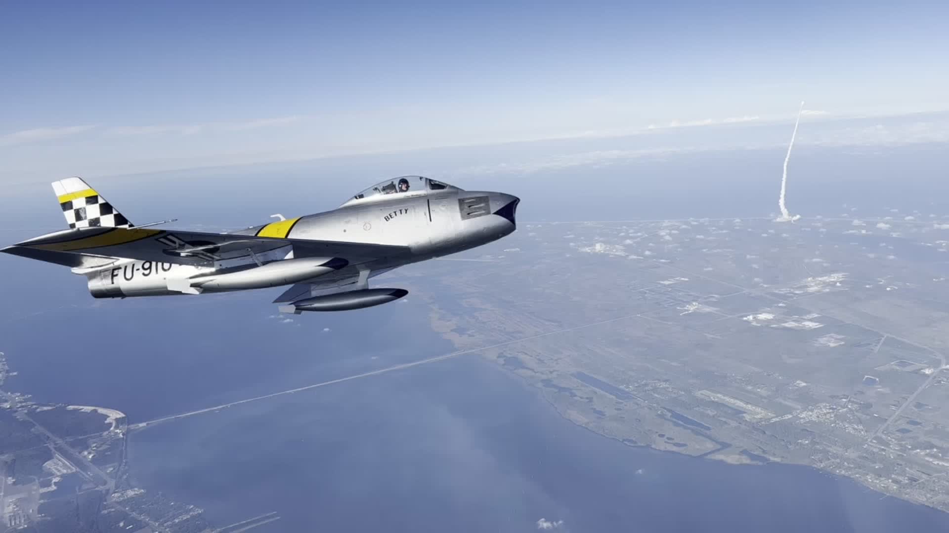 Vintage Fighter Jet Soars as Rocket Launches