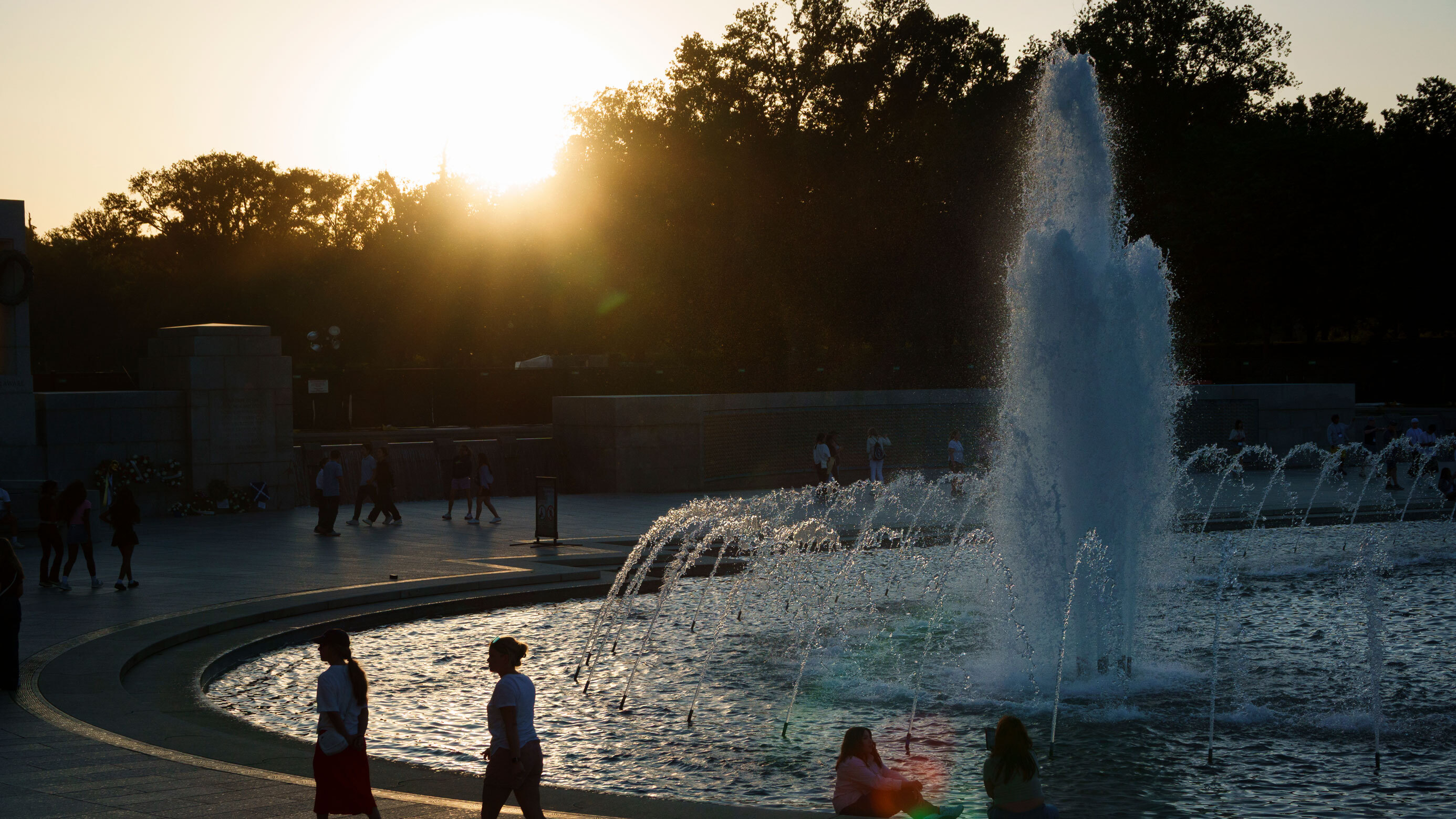 People walk around the World War II Memorial in the National Mall at sunset on May 28, 2026 in Washington, DC.