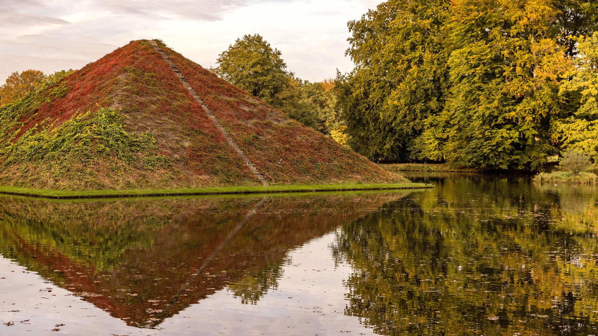The water pyramid in Branitz's Prince P&uuml;ckler Park &mdash; the final resting place of the prince and his wife Lucie &mdash; is overgrown with grapevines, which are currently turning a deep red. At sunset, the pyramid is reflected in Lake Tumulus. Rain is expected in the region starting tomorrow.