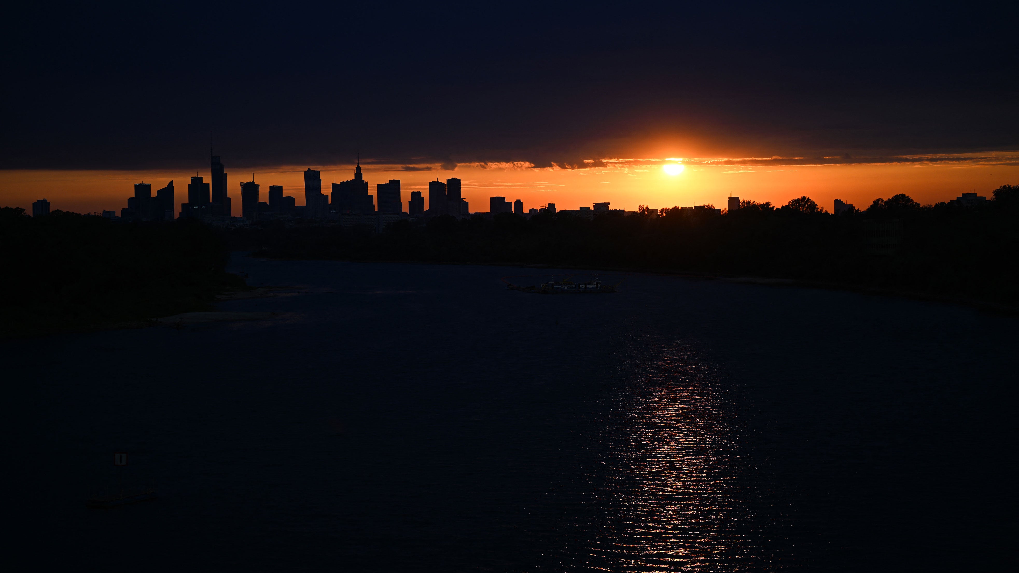 Warsaw's skyscrapers are silhouetted as the sun sets over the Vistula River on Aug. 6, 2026.