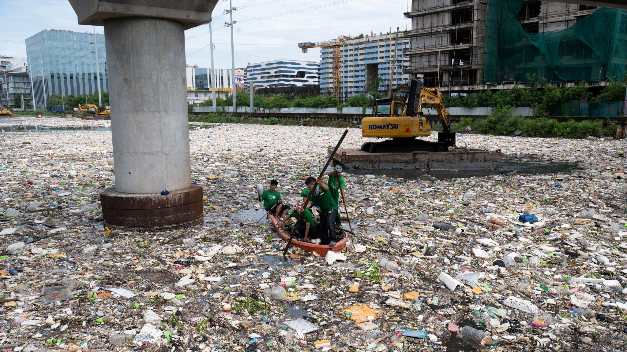 Workers on a plastic boat collect trash washed up on a river at the height of heavy rains enhanced by the Southwest monsoon near a shopping complex in Paranaque City, suburban Manila on Tuesday, Aug. 11, 2026. Floods, landslides and accidents driven by a nine-day downpour equivalent to more than a month's worth of rain in some areas have killed at least 16 people in the northern Philippines.