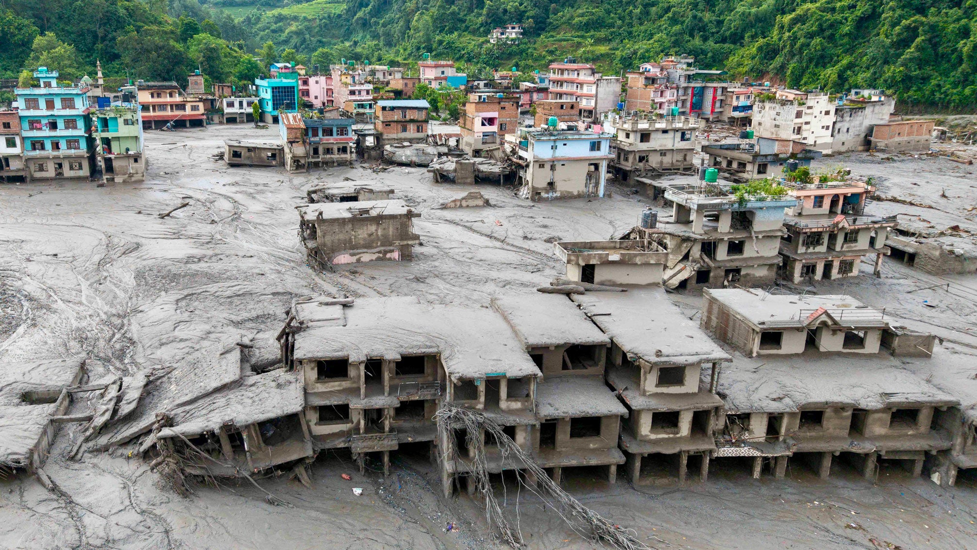 An aerial view shows houses lying deluged in sludge after flash floods at Devighat, Bidur Municipality in Nepal's Nuwakot district on Thursday, Aug. 27, 2026. Nepal's disaster agency said that 823 people remained out of contact on Aug. 27, more than 24 hours after a deadly flood tore through the border region with Tibet.