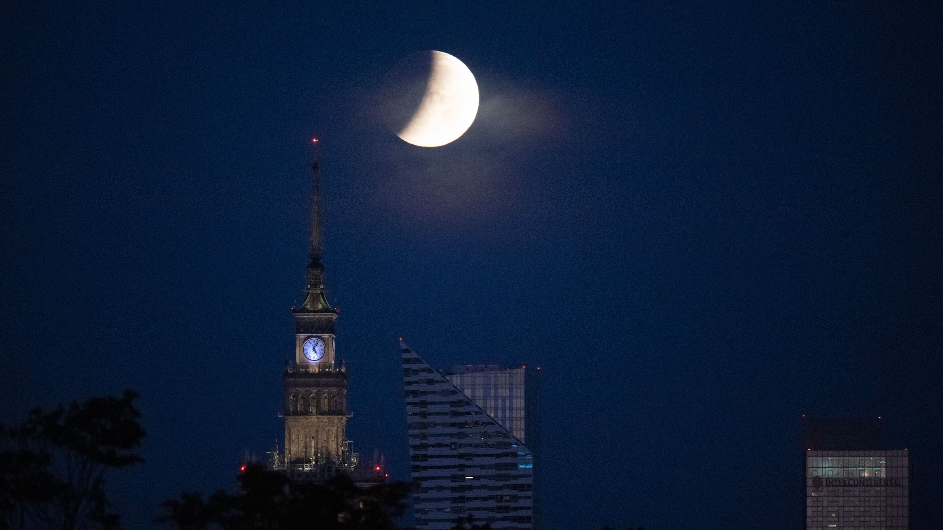 The full moon, also known as the Sturgeon Moon, sets over Warsaw's skyscrapers during a partial lunar eclipse in Poland on Thursday, Aug. 28, 2026.