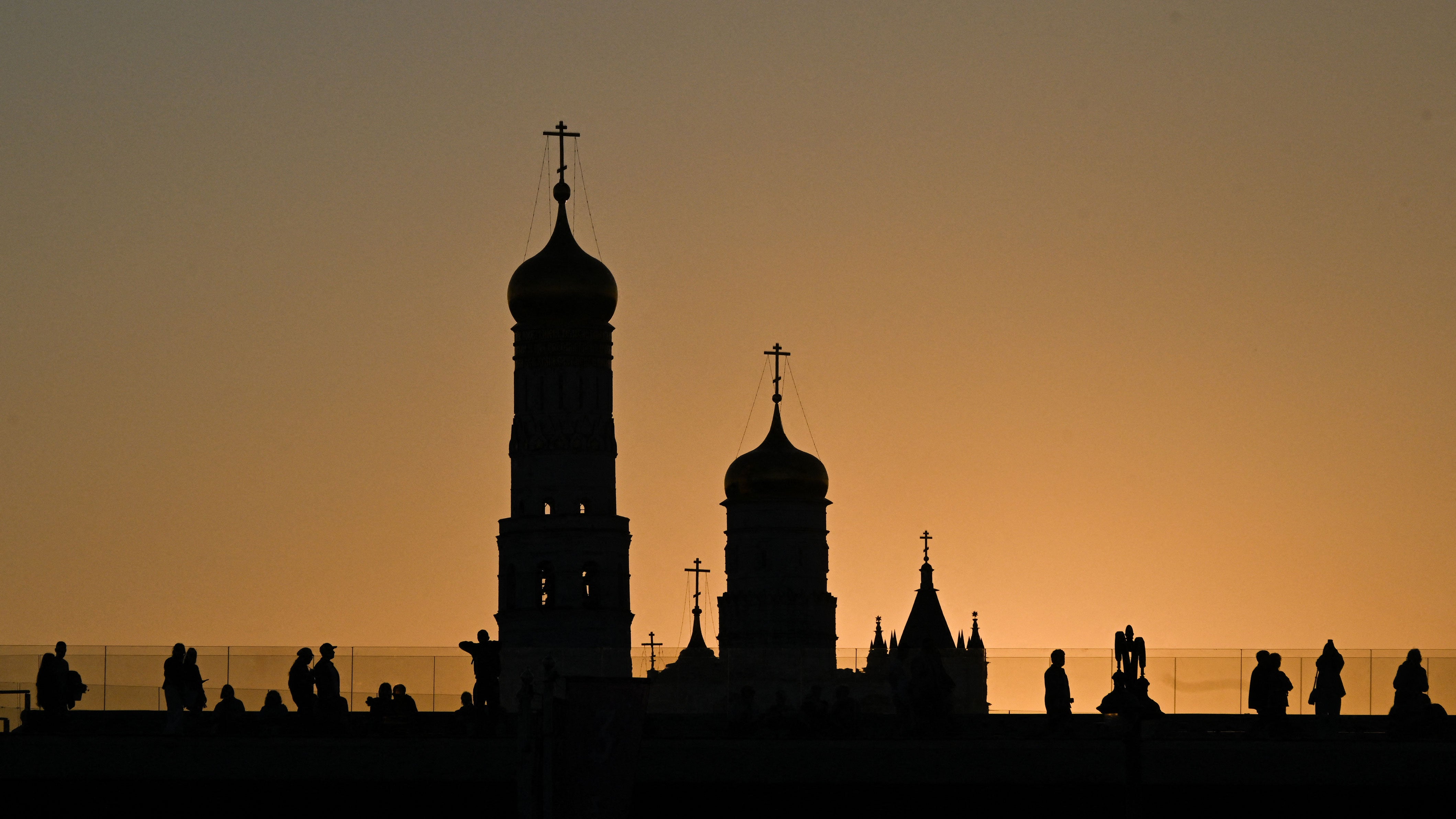 People walk on the floating bridge in Zaryadye park, with the Cathedral of St. Nicholas the Wonderworker of Gostun appearing in the background, during sunset in central Moscow on Aug. 31, 2026.