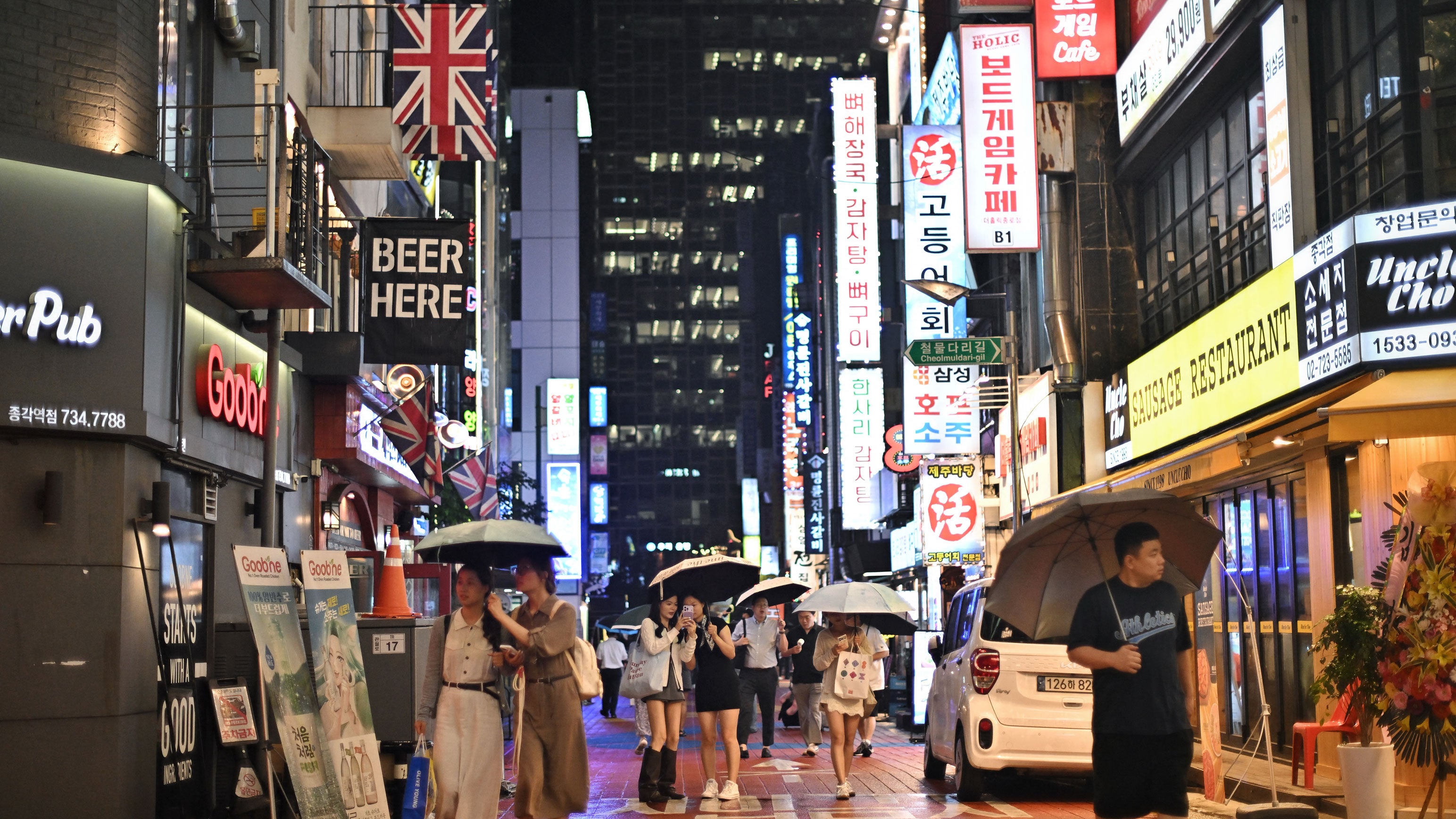 Pedestrians walk past bars and restaurants in the rain in Seoul, South Korea on Tuesday, Sept. 1, 2026.