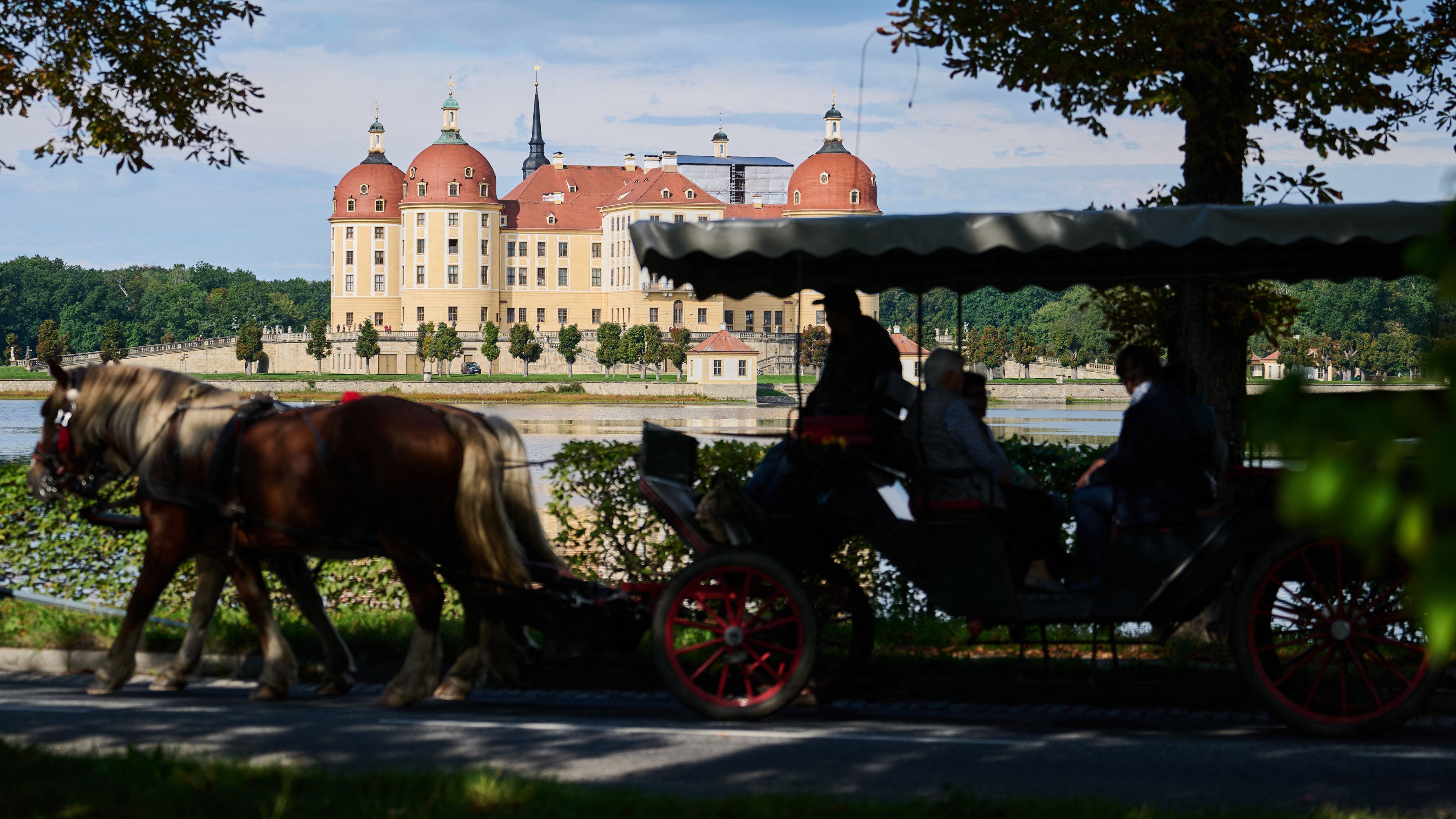 The sun is shining on Moritzburg Castle, the former hunting lodge of the Wettin dynasty near Dresden, as a horse-drawn carriage passes by on Sept. 16, 2026, in Moritzburg, Saxony, Germany.