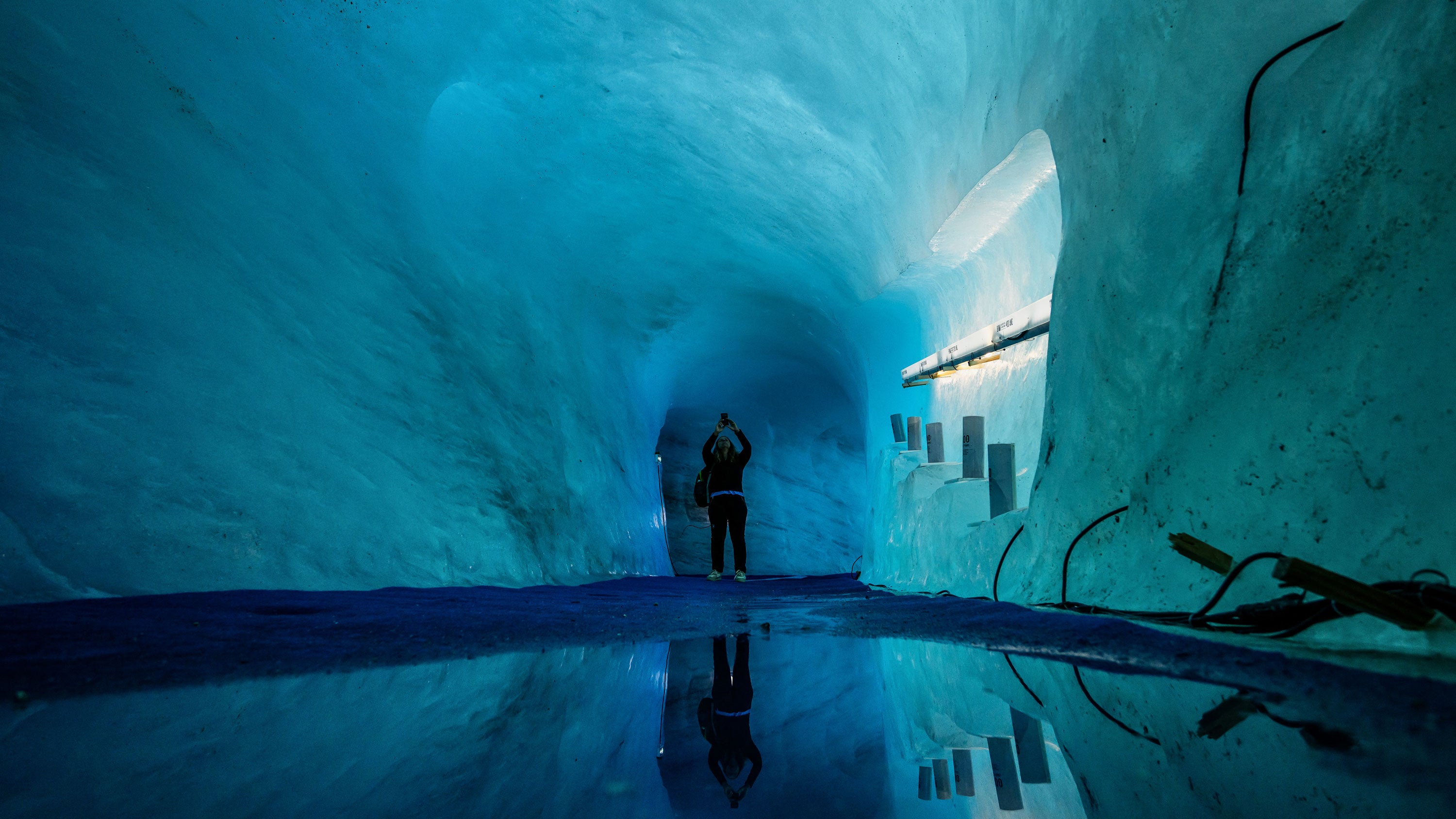 A tourist visits the Mer de Glace Ice Cave in the "Mer de Glace" glacier in the Mont Blanc Massif, French Alps, central-eastern France, on Sept. 23, 2026. The ice cave located under the Mer de Glace is covered with geotextile tarps to slow down the melting of the glacier caused by particularly high temperatures due to successive heat waves in the summer. The Mer de Glace glacier is undergoing an accelerated melting down due to climate change.