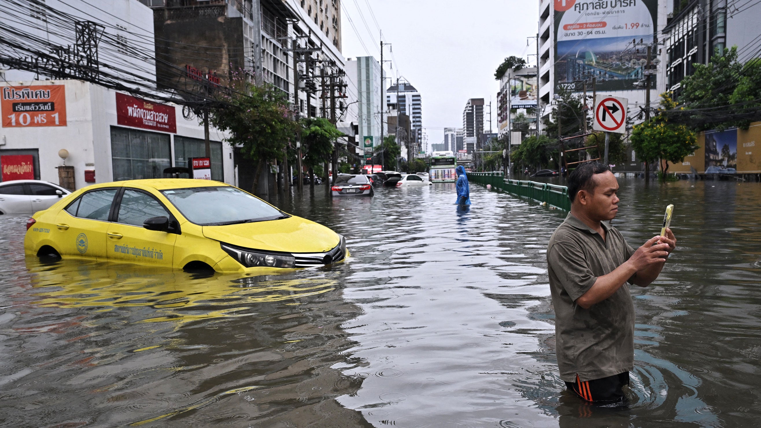 People film near abandoned cars along a flooded Petchaburi road in Bangkok, Thailand, on Sept. 26, 2026. Bangkok authorities declared a flood disaster across the Thai capital after almost 48 hours of heavy rain left canals full, roads submerged and residents wading through deep water.