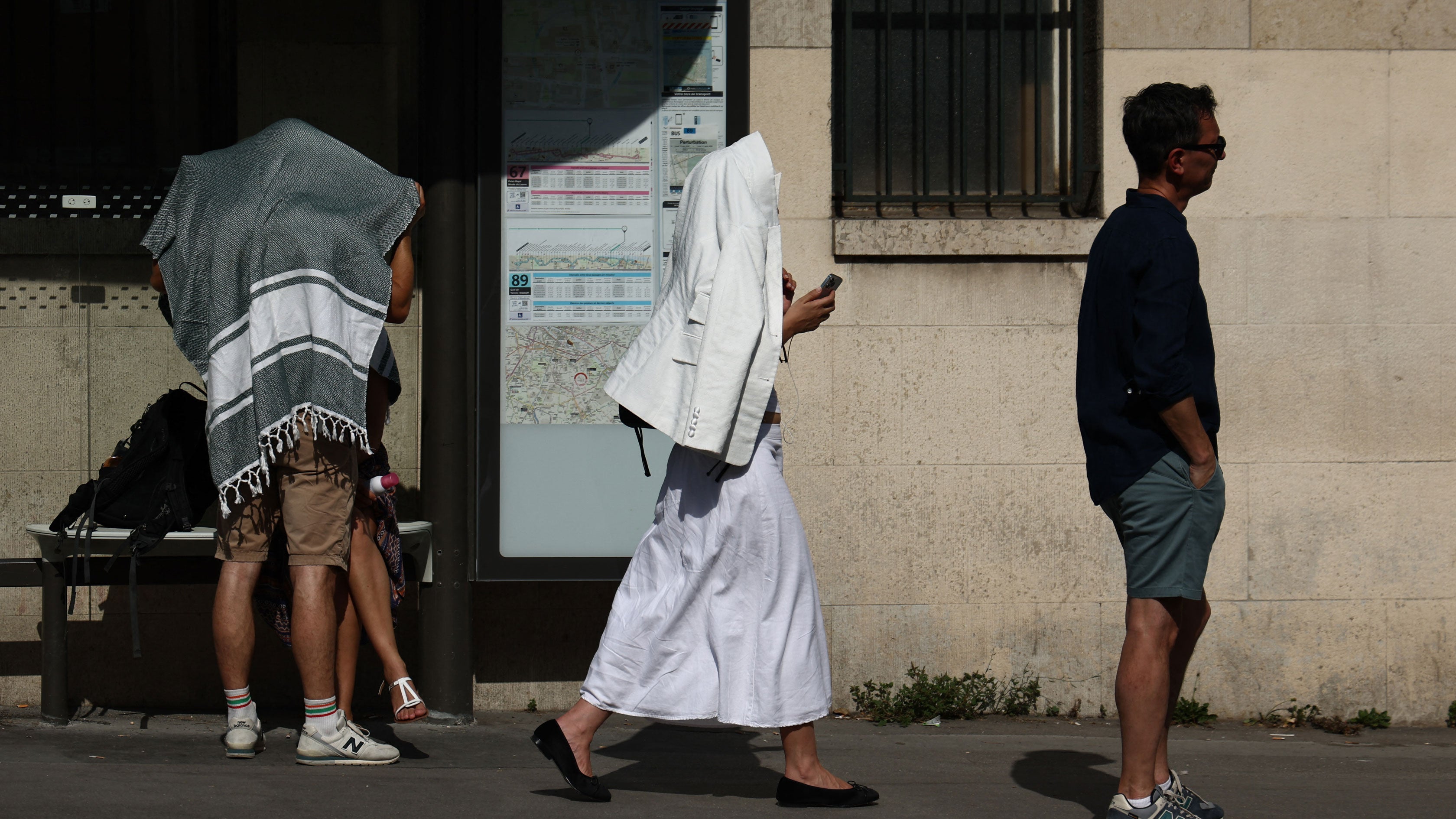 People cover themselves to protect from the sun near the Jardin des Plantes during a heatwave in Paris, Ile-de-France, France, on June 20, 2026.