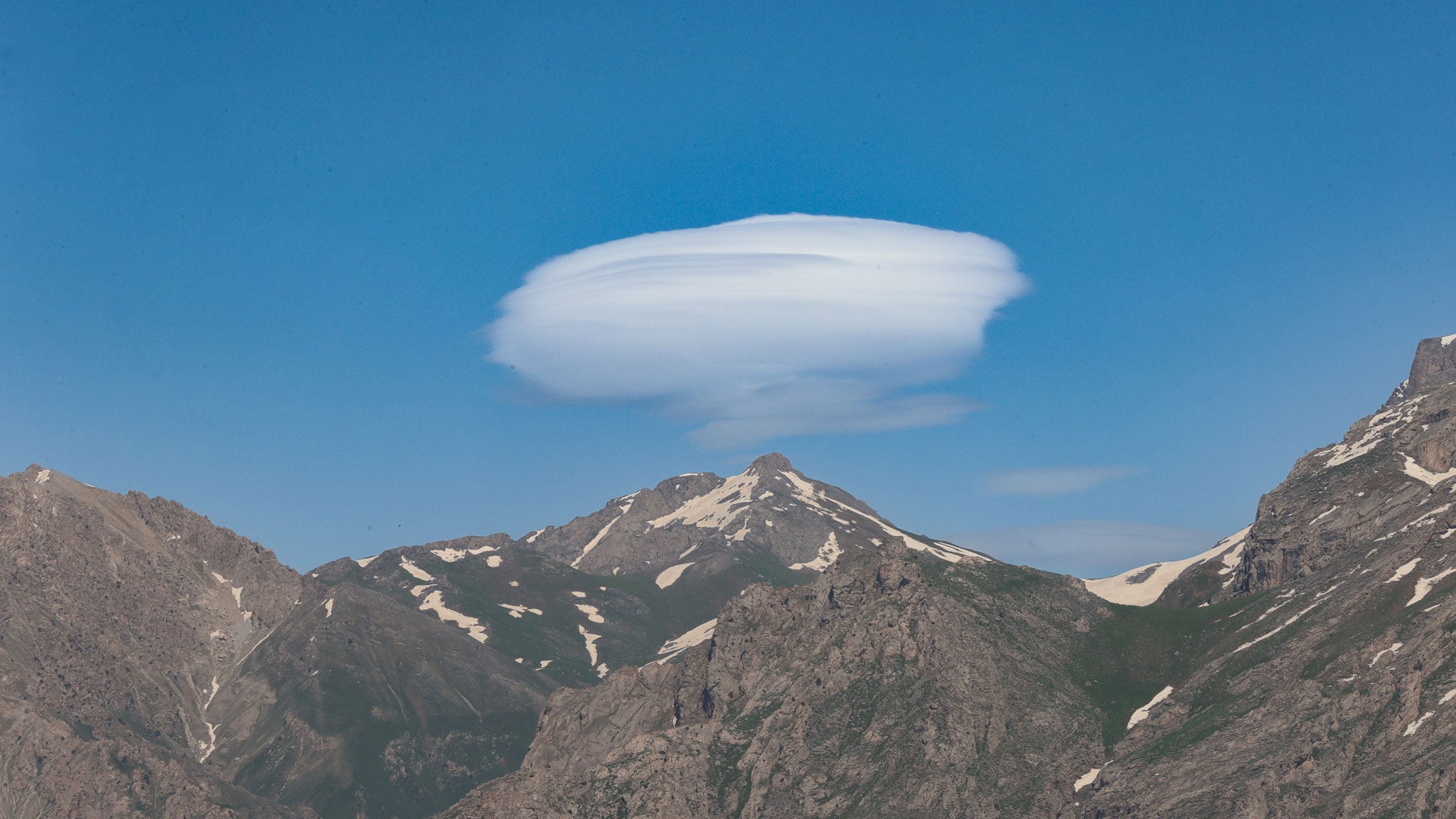 Lenticular clouds form over Mount Sumbul, a 3,487-meter peak in Hakkari, eastern Turkiye, where patches of snow remain on parts of the summit, on June 12, 2026. The distinctive cloud formation appears above the mountain, creating a striking landscape in the region. 