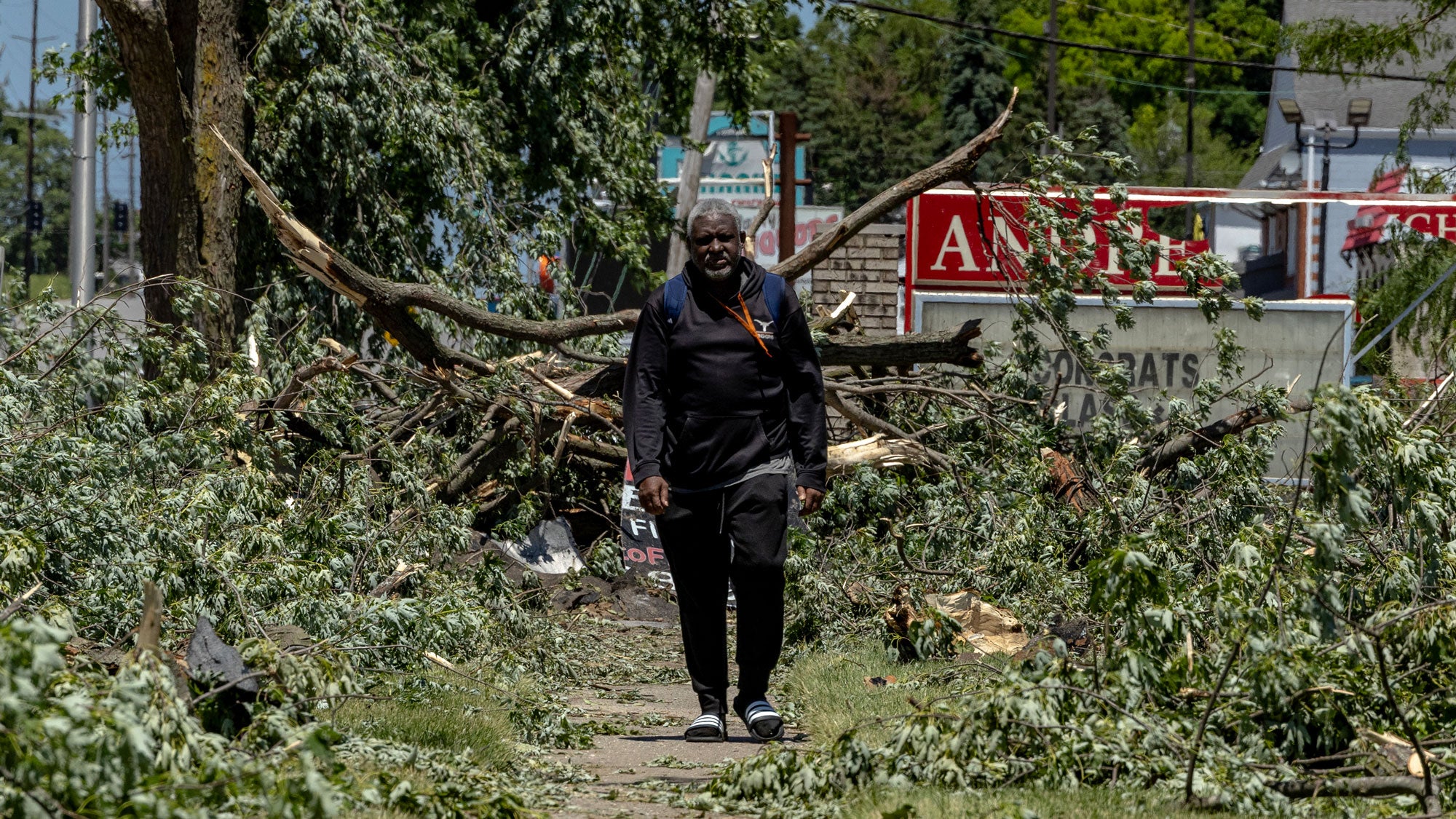 A man walks through debris in front of Andrean High School after it was damaged by tornado winds on June 12, 2026, in Merrillville, Indiana. A tornado system passed through the area the previous night, causing widespread damage to homes and businesses.