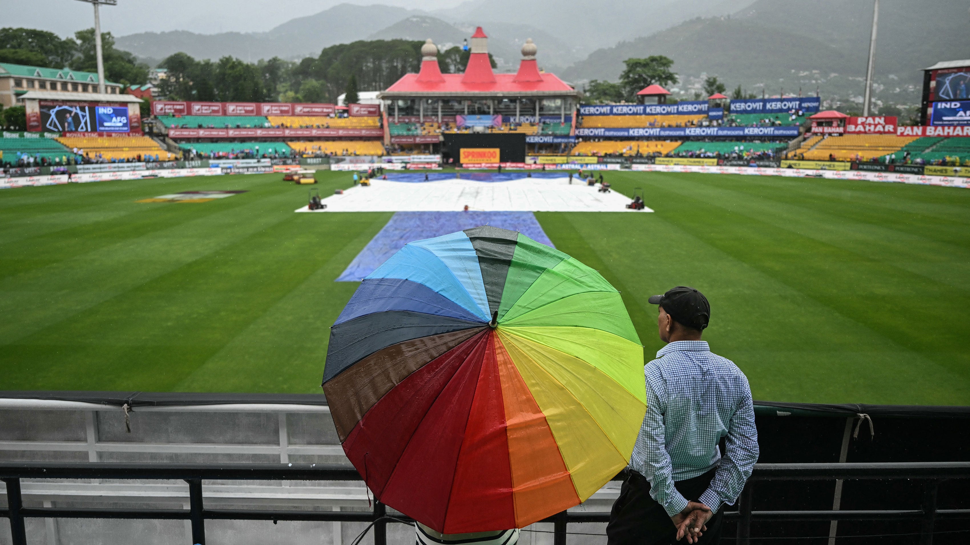 Spectators wait as rain delays the start of the first one-day international cricket match between India and Afghanistan at the Himachal Pradesh Cricket Association Stadium in Dharamsala on June 13, 2026.