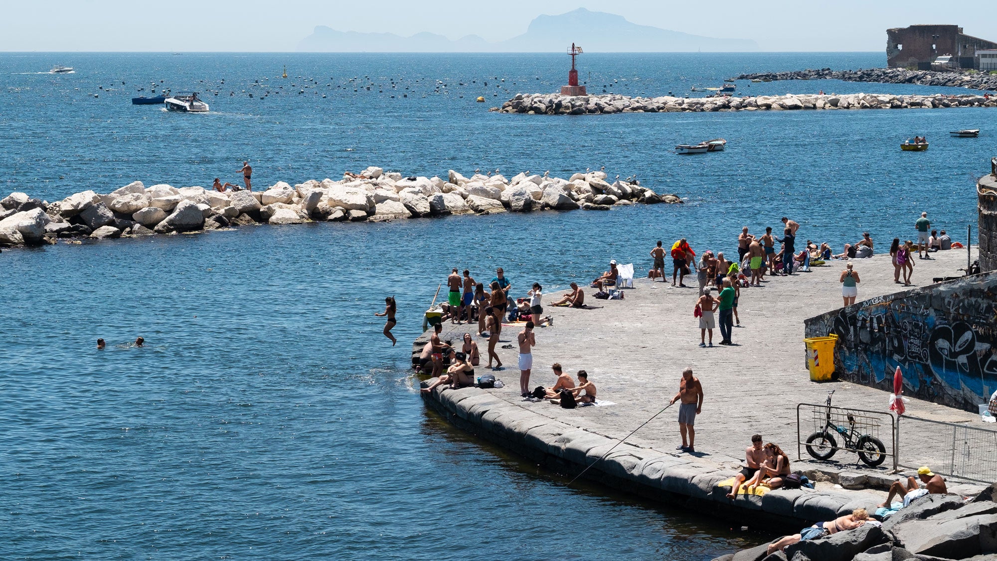 People sunbathe and swim during the African heatwave in Naples, Italy, on June 19, 2026.