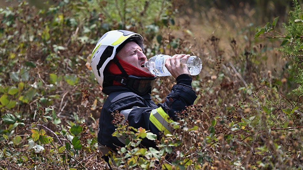 A firefighter drinks from a plastic water bottle